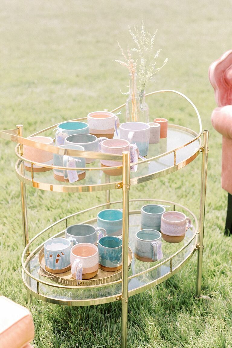Pastel mugs as escort cards on gold bar cart