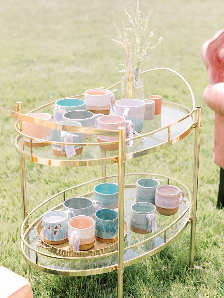 Pastel mugs as escort cards on gold bar cart