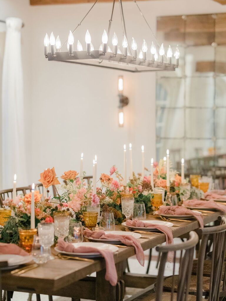 Muted pink and orange flowers and table linens at summer wedding