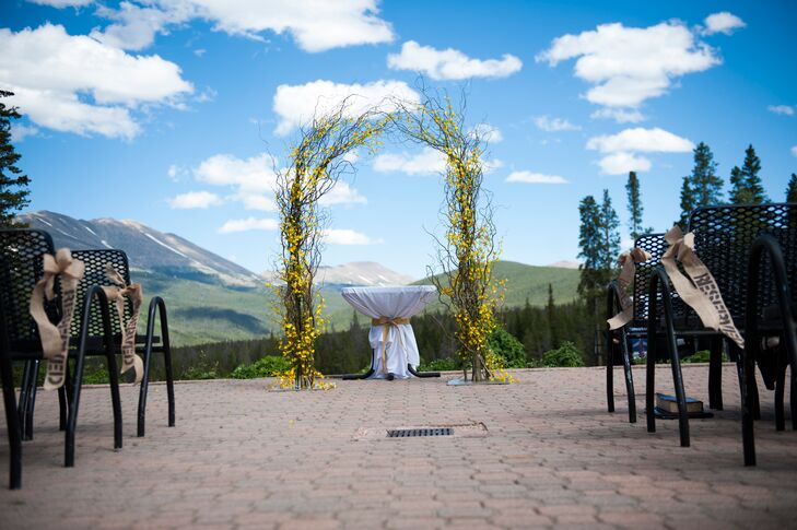 Jessica and Phil exchanged vows under a branch and yellow flower wedding arbor overlooking swoon-worthy views of the mountains.