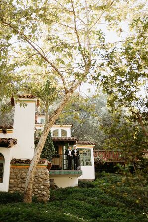 Grooms on a Balcony Overlooking Reception at Spanish-Style Villa at Their Venue