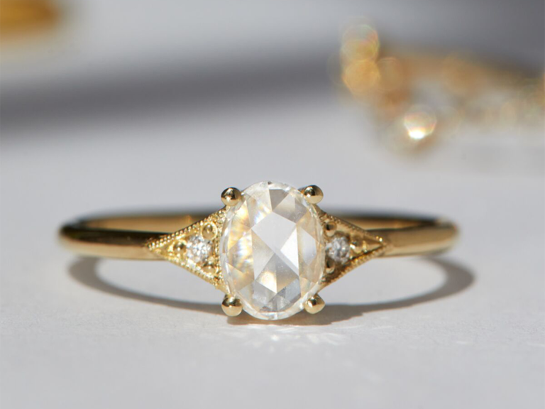 Oval diamond center with gold metal triangle edges and round diamonds on gold band