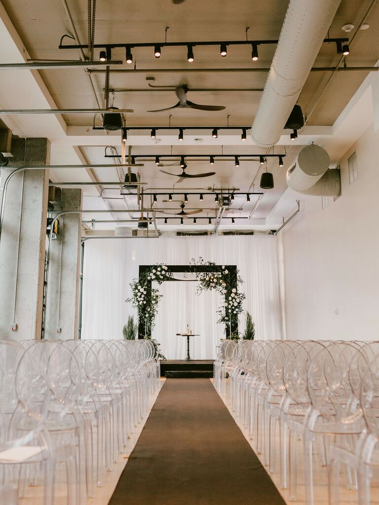 indoor wedding ceremony at industrial wedding venue with white walls, concrete floors and exposed ductwork on ceiling