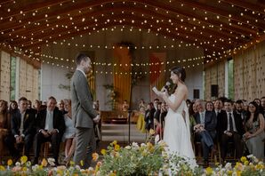 Bride and Groom Reading Vows Under String Lights With Colorful Flowers