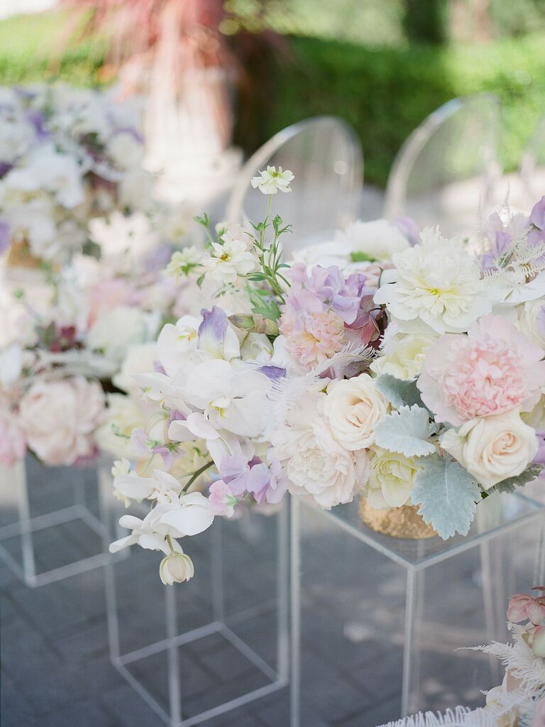 pastel wedding flower arrangements with pink peonies, purple sweet peas, white orchids and dusty miller on acrylic rectangular stands