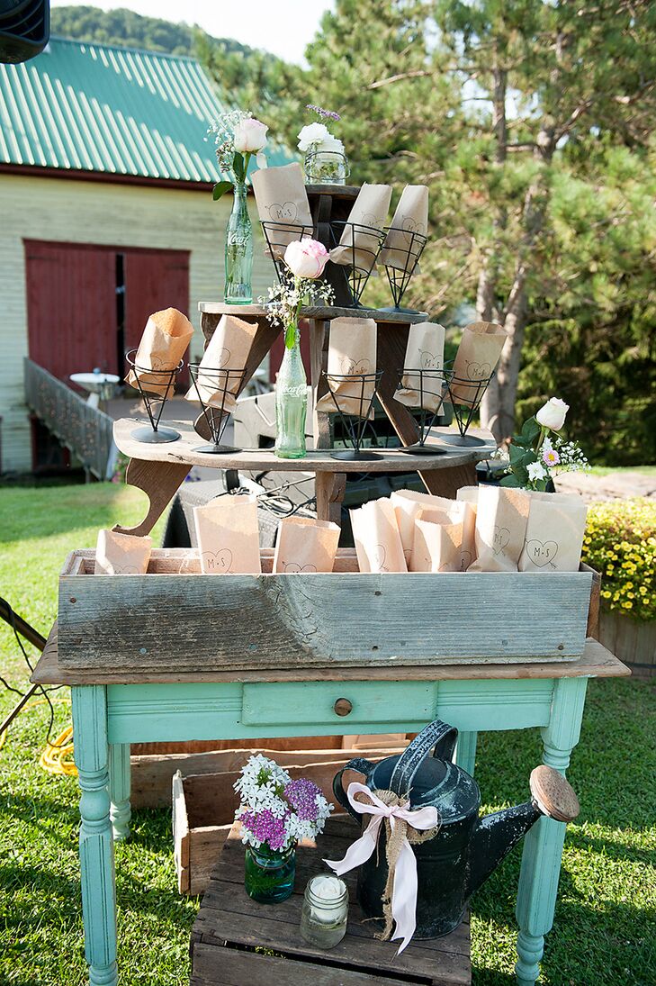 As guests arrived at Mary and Sam's wedding ceremony, they found a popcorn machine and paper bags stamped with Mary and Sam's initials for filling with the popcorn.