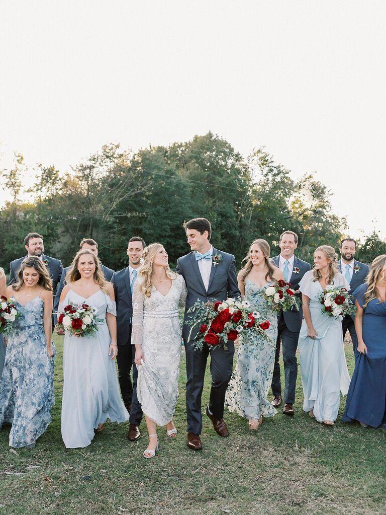 bride and groom walk with wedding party wearing mix-and-match printed blue bridesmaid dresses