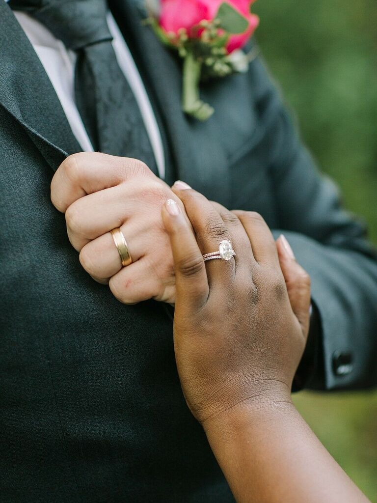 Bride wearing oval engagement ring with her hand on husband's chest