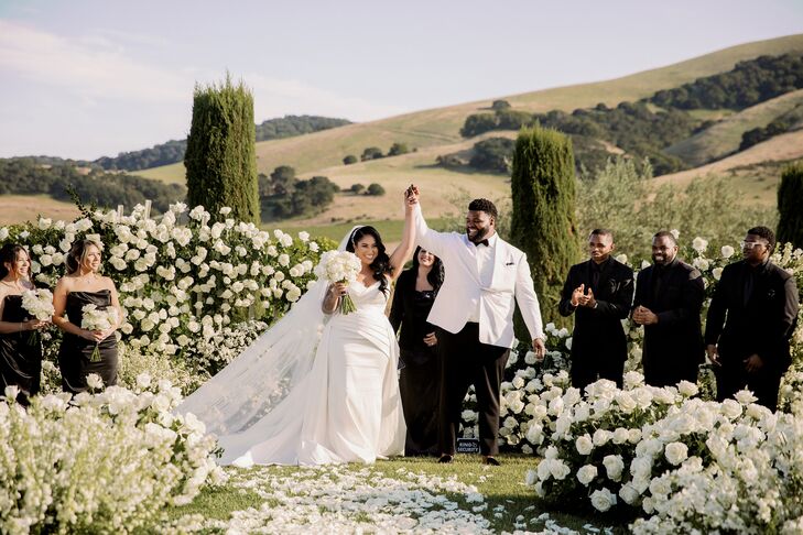 Couple Holding Hands After Outdoor Wedding Ceremony Surrounded by Roses