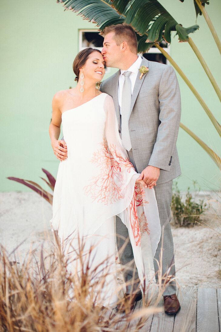 Traditional just wasn’t going to cut it for Whitney, when it came to her wedding day look. “I really wanted a dress that was unique, but struggled to find something that wowed me,” she says. She came across what would become her wedding dress, while scanning Pinterest. “The dress was from a designer in California, so I tracked down the phone number and called not expecting for anything to work out,” says Whitney. But to her surprise, the designer had one dress left and it happened to be in her size. The one-shoulder column gown by Blac Mera featured an airy overlay decorated with a hand-painted red tree that added a pop of playful color. Whitney kept the rest of her look simple, adding a pair of crystal drop earrings and a ring that her great-grandparents made for her mother. “The diamond is so tiny, but carries so much meaning,” says Whitney. “They were married for almost 70 years.”rn