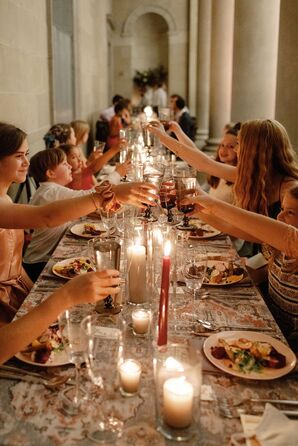 Guests Cheers Glasses Over Long Reception Table With Candles in Museum