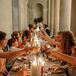 Guests Cheers Glasses Over Long Reception Table With Candles in Museum