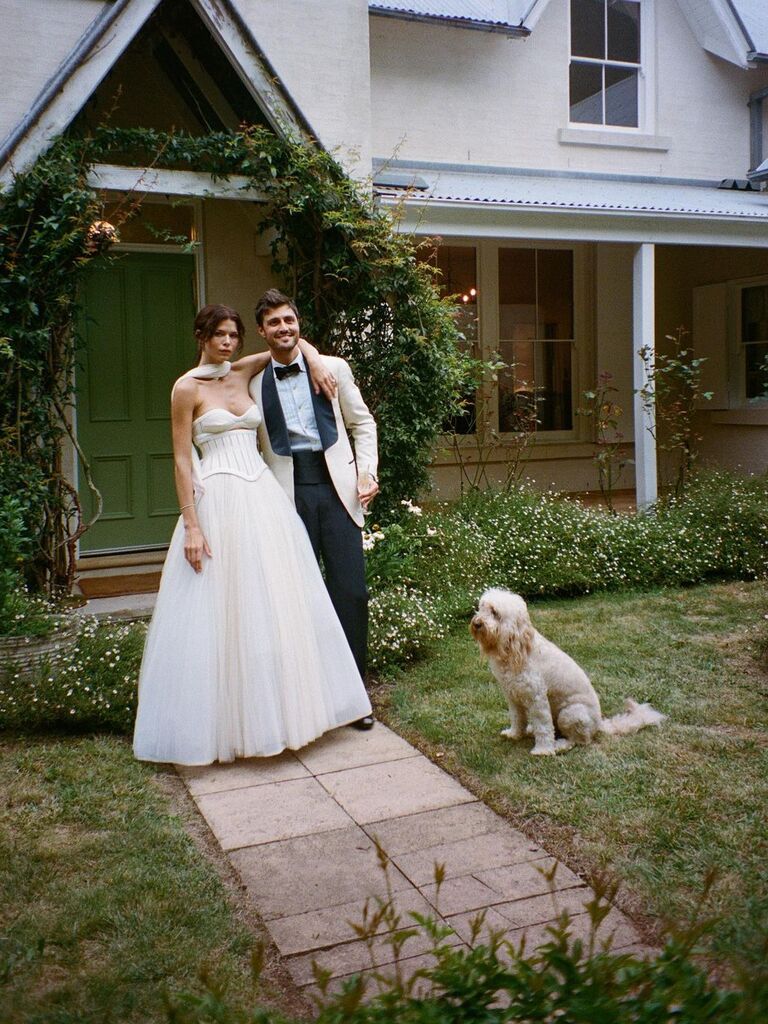 Georgia Fowler and her husband pose for the camera in front of a beautiful house. 