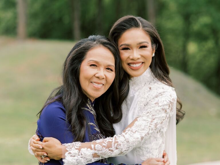 Mother and the bride hug while smiling for the camera. 
