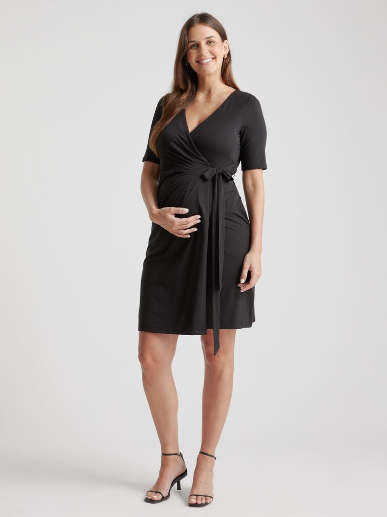 Model wears a black wrap maternity dress. 