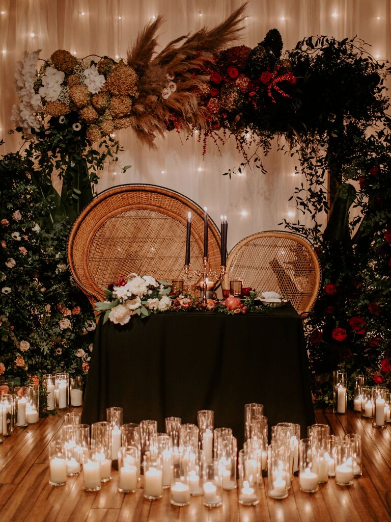 sweetheart wedding table with rattan peacock chairs, black taper candles and white pillar candles on the floor in front