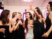 bride and bridesmaids singing karaoke at wedding reception