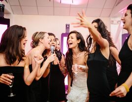 bride and bridesmaids singing karaoke at wedding reception