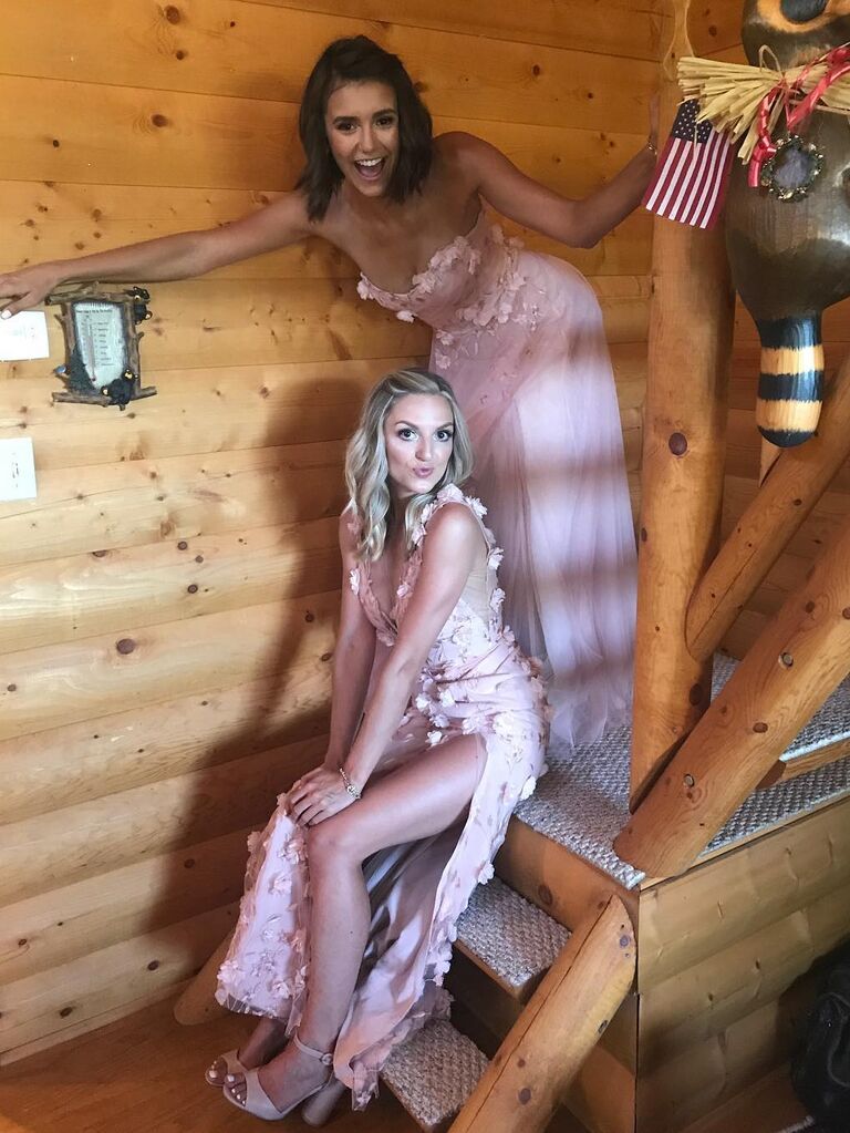 Nina Dobrev wears a strapless pink gown and smiles for the camera with a friend. 