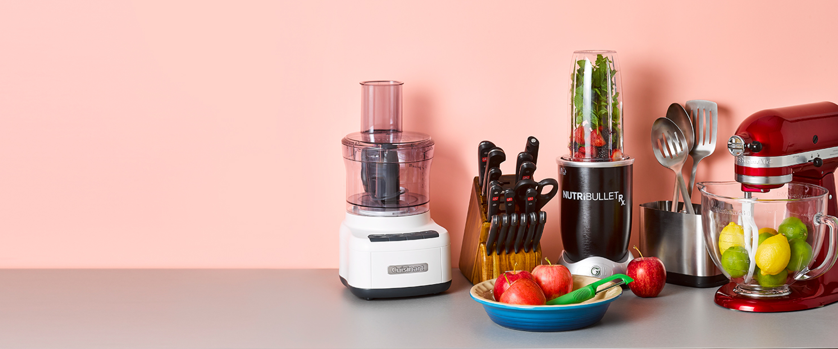 Popular registry items arranged together including a Cuisinart food processor, Wüsthof‎ knife set, Nutribullet blender, kitchen utensils, and a KitchenAid mixer.