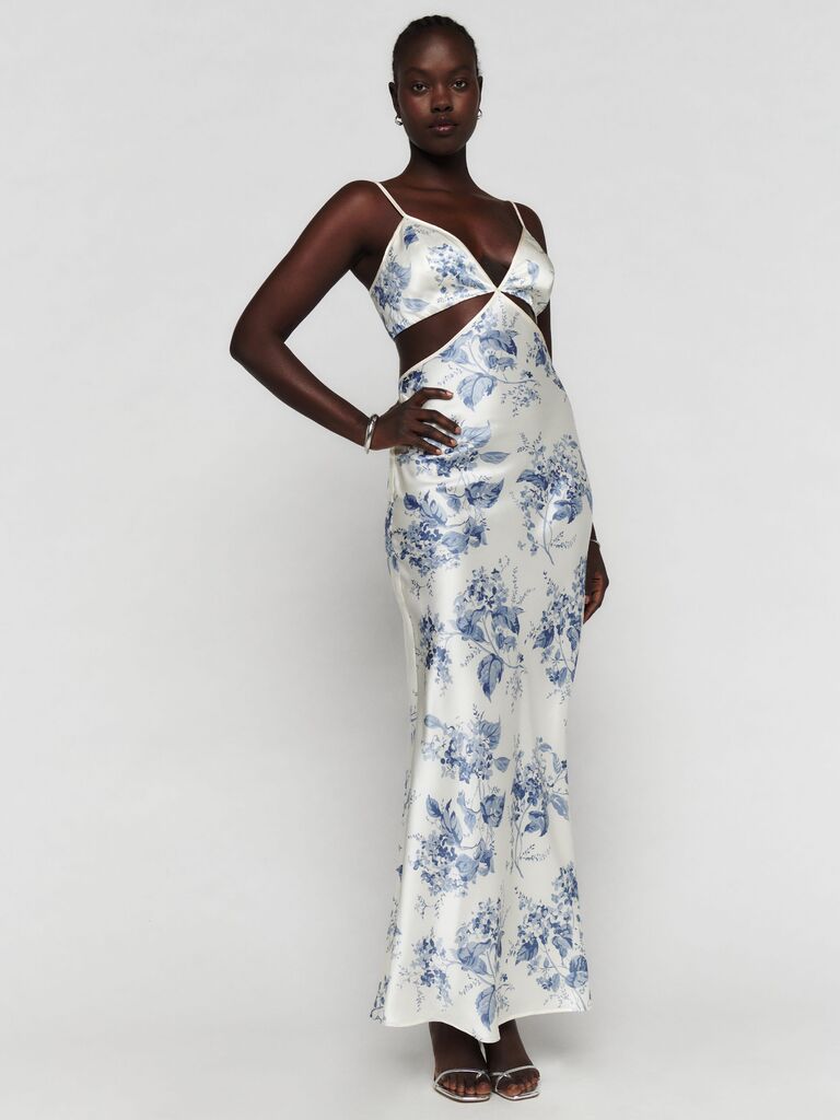 A silk maxi dress in cream with a blue floral motif, plunge v neckline, and waist cutouts from Reformation