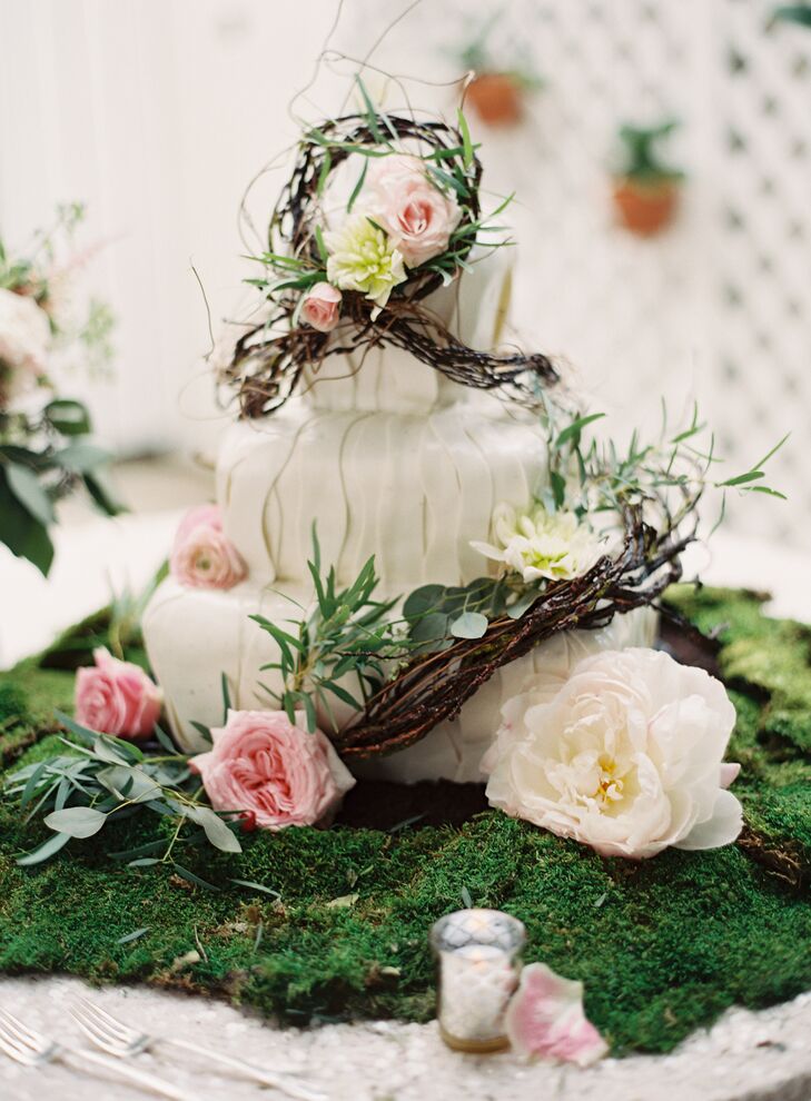 The couple chose a whimsical garden inspired three-tiered wedding cake baked by Johnson’s Custom Cakes & More. It was complemented with cream peonies, pink garden roses and pink ranunculus. “We wanted the cake to seem as though it were part of the decorated room, and not a foreign piece of focus,” says Joyce.