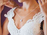 Bride putting on necklace