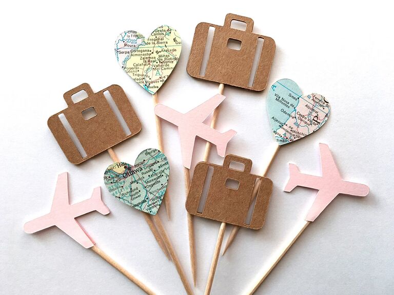 Paper cupcake toppers in pink airplane, brown luggage and heart cut out of map