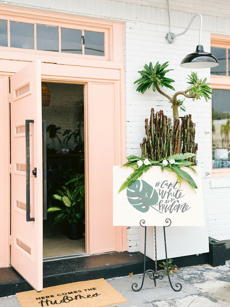 A tropical welcome sign with the wedding hashtag "#Can'tWhiteToBeAHudome"