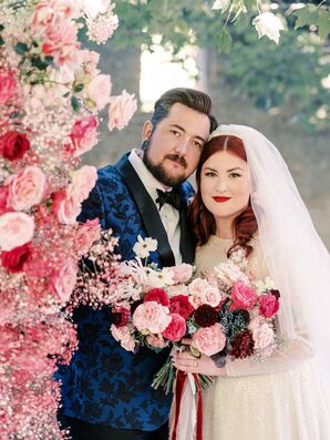 Bride in Long Veil and Groom in Navy, Floral Suit Jacket Pose With Pink Flowers