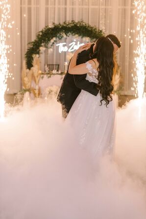 Couple Hugging During First Dance While Surrounded by Fog and Sparklers