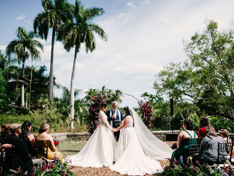 Brides saying vows during outdoor tropical wedding ceremony
