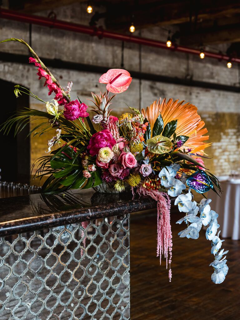wedding bar decorated with magenta, orange, blue and purple floral centerpiece