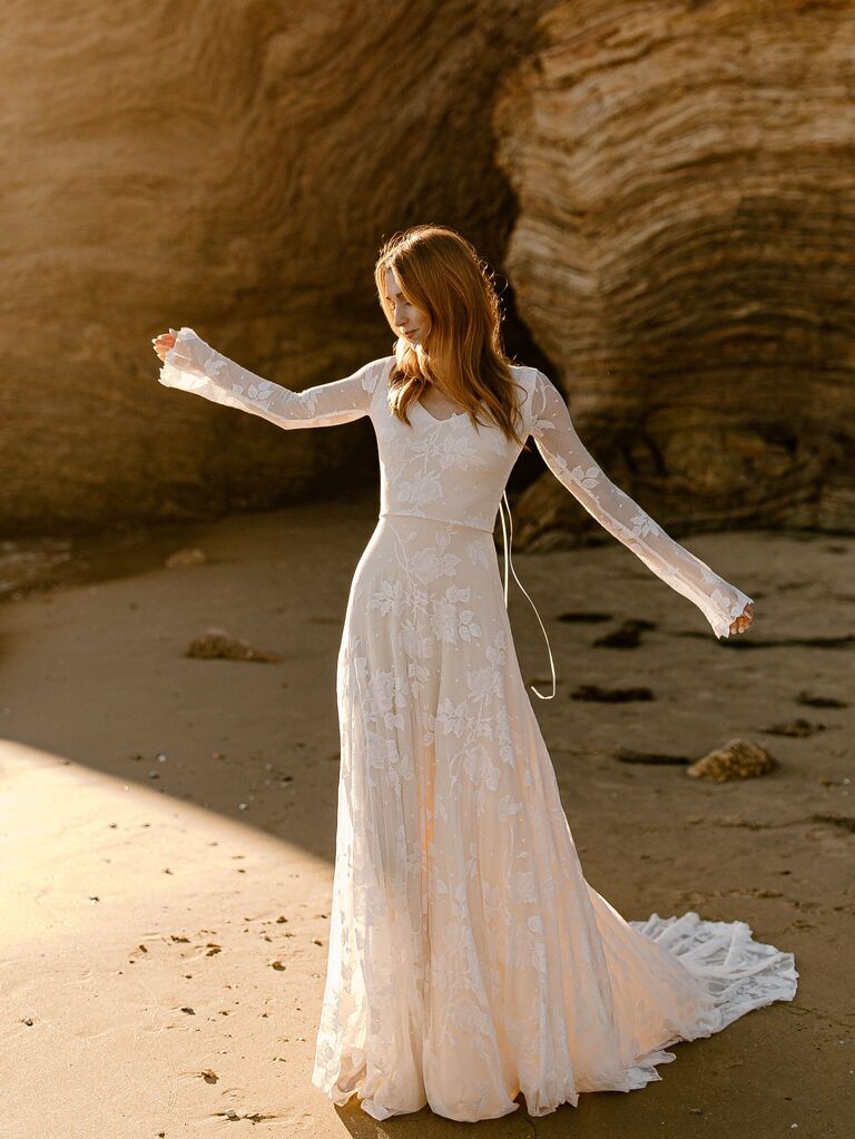 Model wears a bohemian long sleeve wedding dress. 