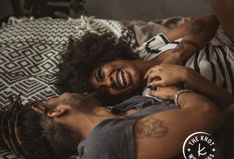 woman and man smiling together while lying on bed