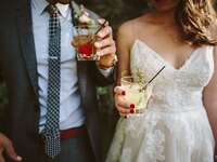 Bride and groom hold colorful cocktails. 
