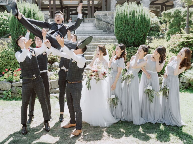 Funny groom and groomsmen photo with groomsmen throwing groom in the air