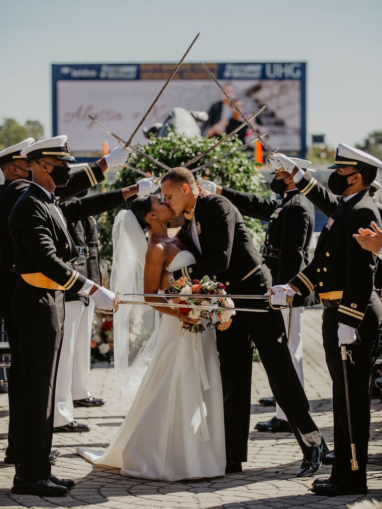 couple kissing under military saber arch at wedding