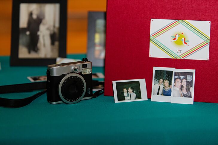 A red guest book was placed on a table decorated with family photos and an instant camera.