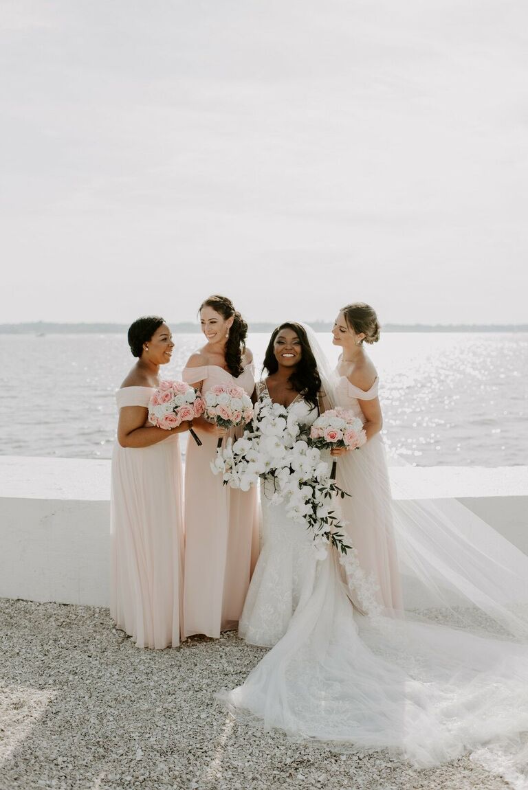 Bride and bridesmaids posing on waterfront 
