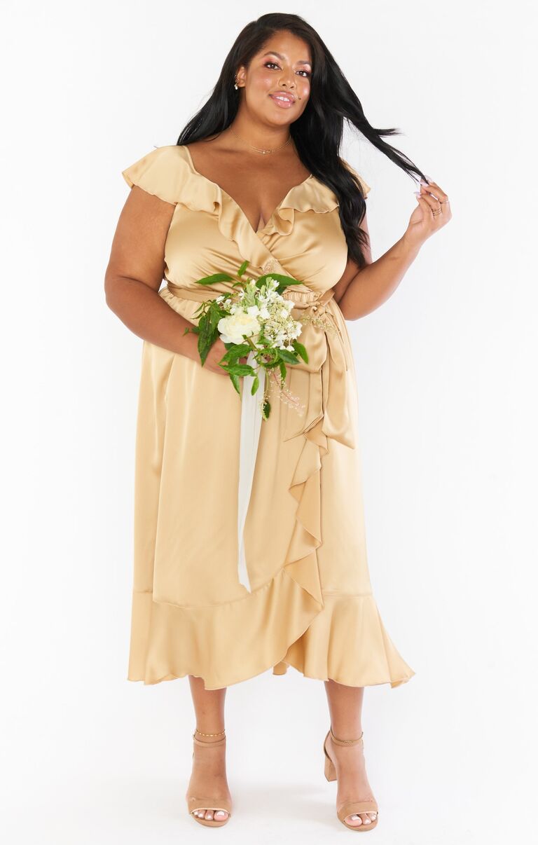 Model wears a golden silk gown with a ruffled hem. 