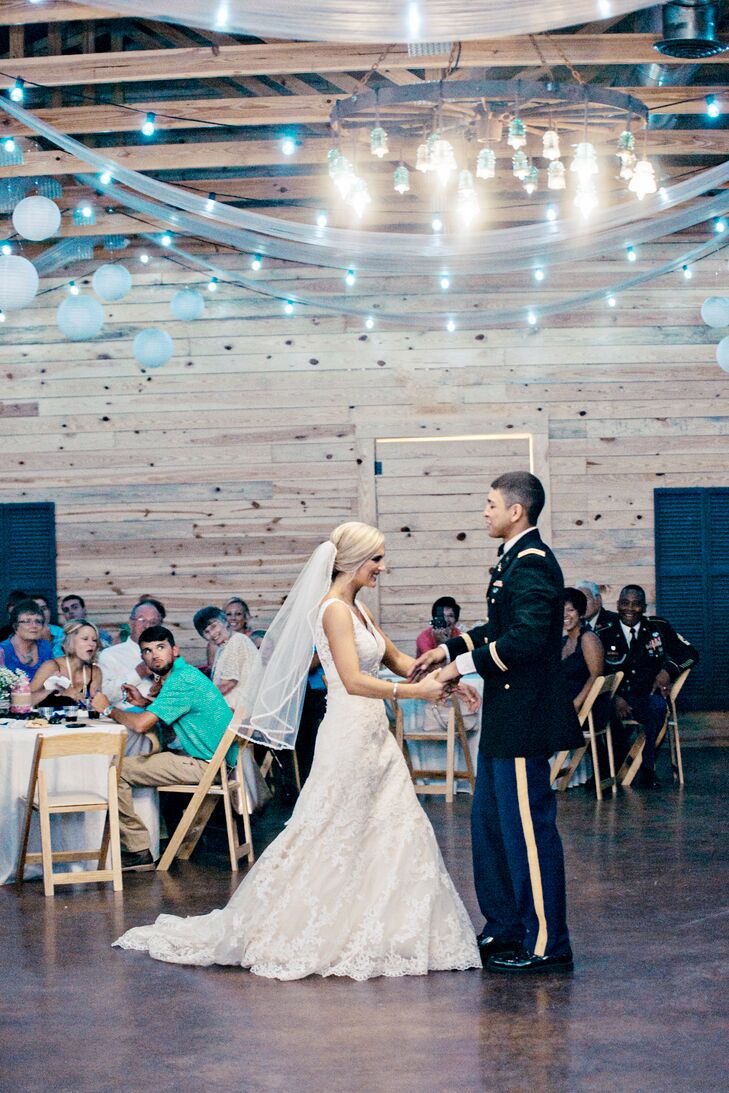 For their first dance, Samantha and Chris selected "I Don't Dance" by Lee Brice. String lights and an iron chandelier created a romantic glow inside the rustic wooden reception barn.