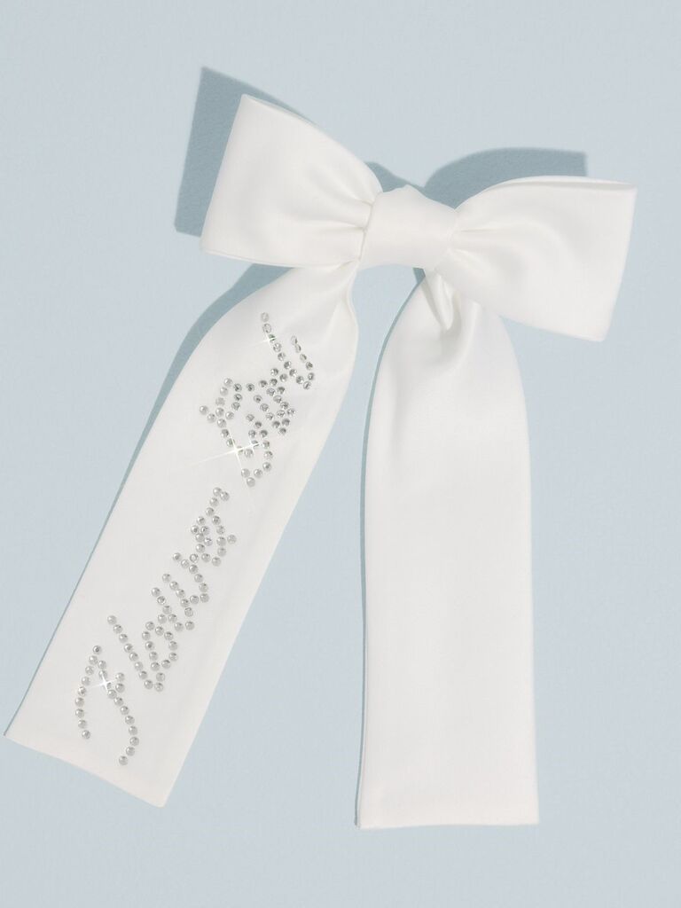 White bow that says "Flower Girl" on it in rhinestones. 