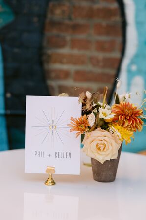 Minimalist Table Number Sign Beside Vase With Roses and Chrysanthemums
