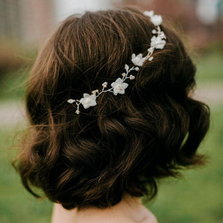 Bride wears her hair in loose curls with a white floral crown. 