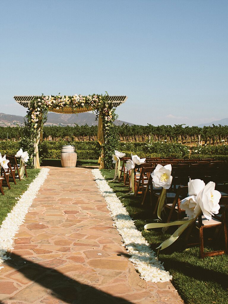 White paper flower decorations for an outdoor ceremony aisle