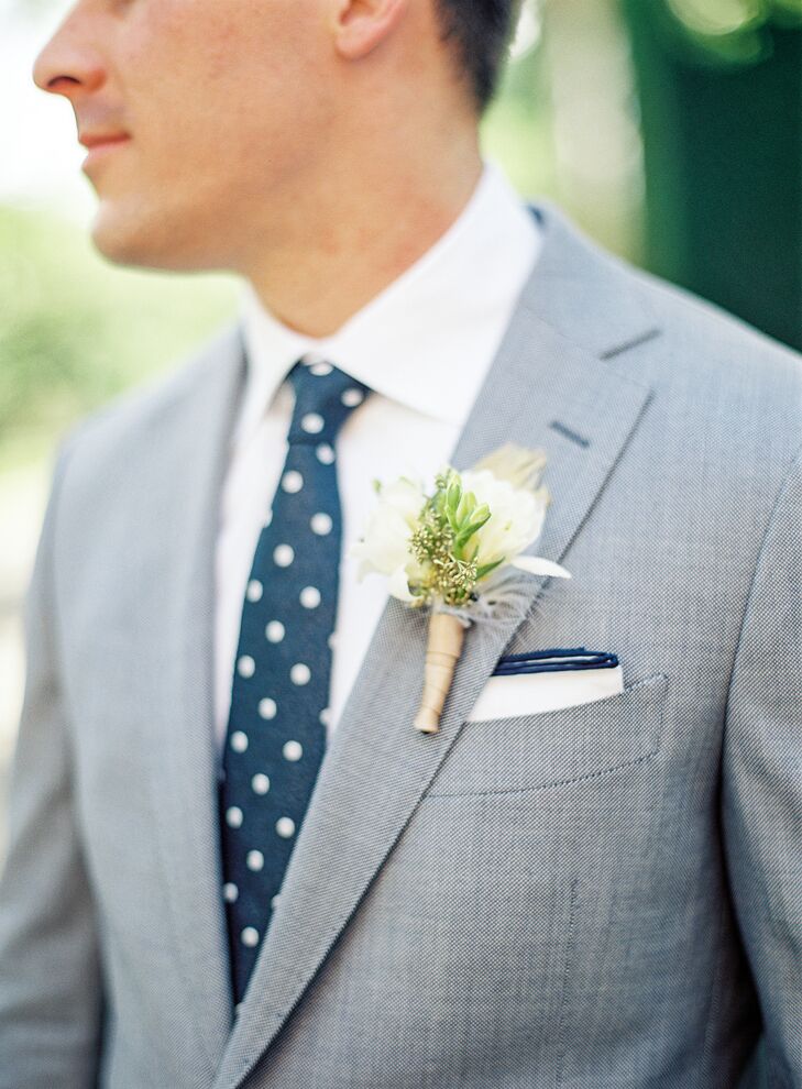 Every part of Joe’s wedding day look had his own personal touch. He suited up in a custom light gray look from Suitsupply with a navy polka-dot tie, a navy-trimmed pocket square and a white shirt. Fitting their summer fete, he donned a natural white freesia, gold-seeded eucalyptus and feather boutonniere on his notched lapel. (As a memento from his Princeton days, Joe also donned his 2006 Ivy League football championship ring.)