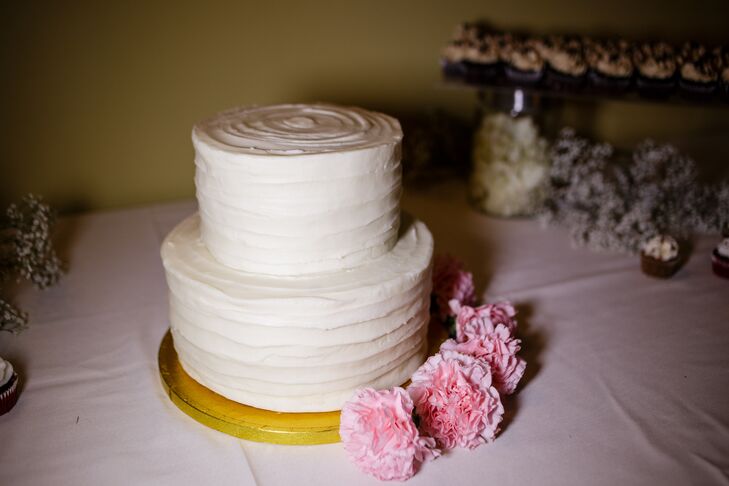 The simple, classic white wedding cake reflected the day's classic theme. The two-tier red velvet cake had buttercream frosting covering its surface, with pink carnations lining the bottom of the gold stand.