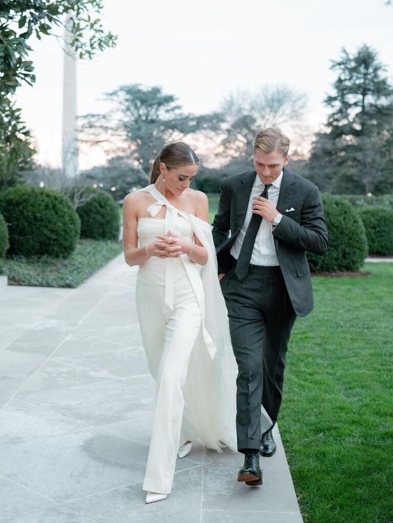 The soon-to-be-weds walk across a green lawn at their rehearsal dinner. 
