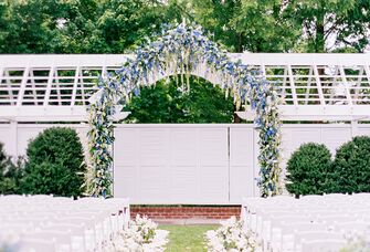 outdoor wedding ceremony venue wih arch of blue flowers at the altar